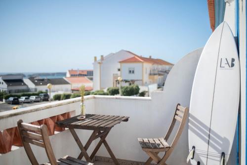 a table and chairs on a balcony with a surfboard at Baleal GuestHouse in Baleal