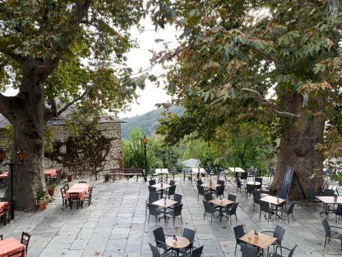 an empty patio with tables and chairs and trees at Archontika Karamarlis in Makrinítsa