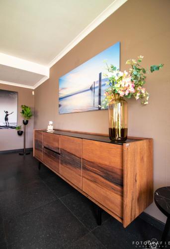 a wooden dresser with flowers in a living room at Zeezicht Sibeac Koksijde in Koksijde