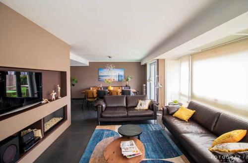 a living room with a couch and a tv at Zeezicht Sibeac Koksijde in Koksijde
