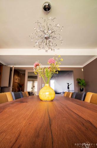 a yellow vase with flowers sitting on top of a table at Zeezicht Sibeac Koksijde in Koksijde