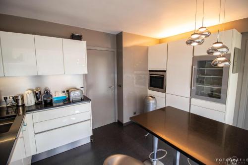 a kitchen with white cabinets and a black counter top at Zeezicht Sibeac Koksijde in Koksijde