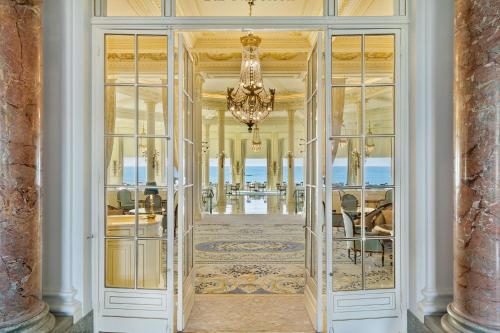 a hallway with glass doors and a chandelier at Hôtel du Palais Biarritz, in The Unbound Collection by Hyatt in Biarritz