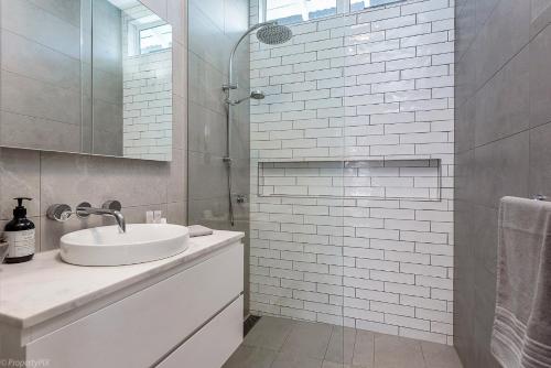ein weißes Bad mit einem Waschbecken und einer Dusche in der Unterkunft Best on Regent, Central location, LUX 3bdm in Sandy Bay