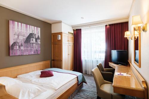 a hotel room with a bed and a desk and a television at Hotel Pelikan in Schwäbisch Gmünd