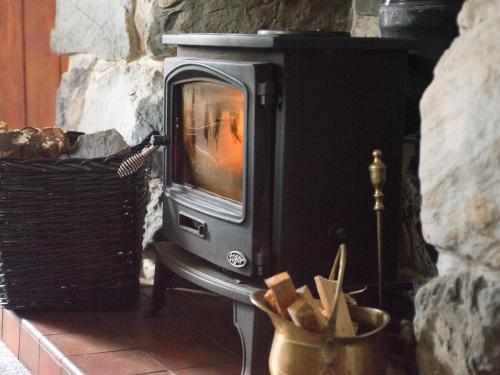 a stone fireplace with a tv in a room at Cae Lleci in Dolgellau