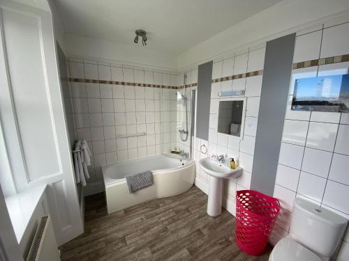 een witte badkamer met een bad en een wastafel bij The Bowmore House Bed and Breakfast in Bowmore