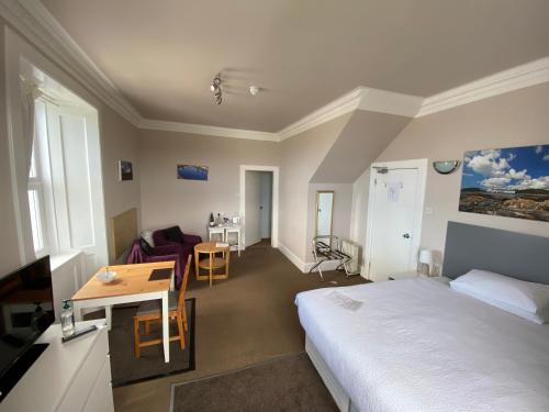 a hotel room with a bed and a desk and a table at The Bowmore House Bed and Breakfast in Bowmore