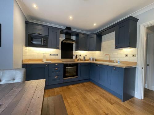 a kitchen with navy blue cabinets and wooden floors at Park View in Keswick