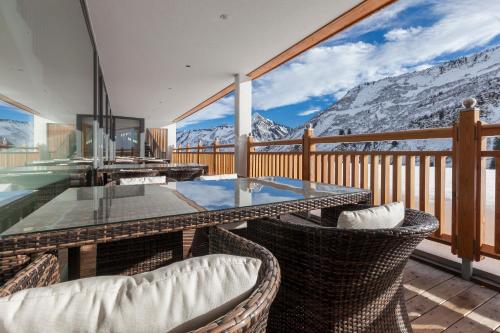 a balcony with a glass table and chairs and mountains at Damülser Hof - Wellness & Spa Superior in Damuls