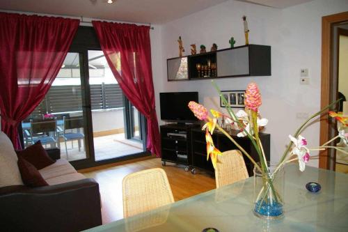 una sala de estar con un jarrón de flores sobre una mesa en Apartamento PR 39 terraza y piscina Tossa de Mar, en Tossa de Mar