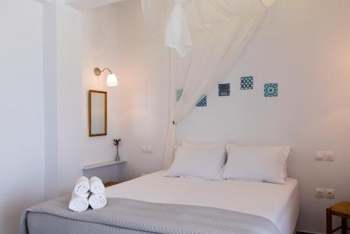 a white bedroom with a bed with two white shoes on it at Ammos Sifnos Village in Platis Yialos Sifnos