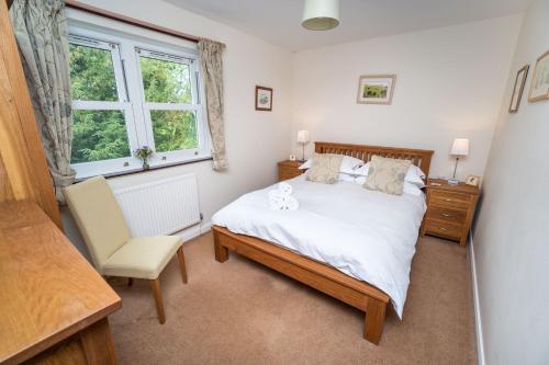 ein Schlafzimmer mit einem Bett und einem Stuhl und einem Fenster in der Unterkunft Quaver Cottage in Keswick