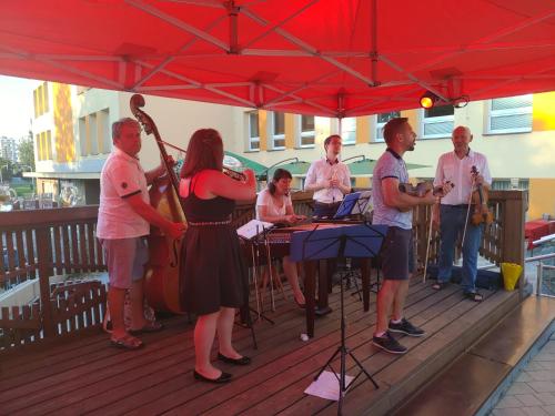 a group of people playing music under a red umbrella at Nábřežní terasy in Žďár nad Sázavou