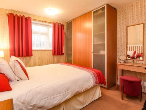 a bedroom with a large bed with red curtains at Old Post Office in Ashford