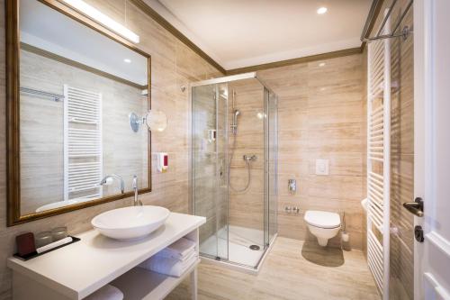 ein Bad mit einem Waschbecken und einer Glasdusche in der Unterkunft Hotel Palace Bellevue - Liburnia in Opatija