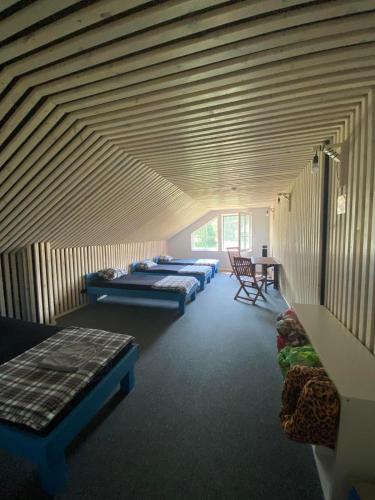 a row of beds in a room with wooden ceilings at Palūšės Kempingas (kambariai) in Palūšė