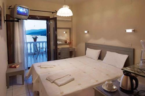 a bedroom with a large bed with a view of a balcony at kirki rooms in Armenistis