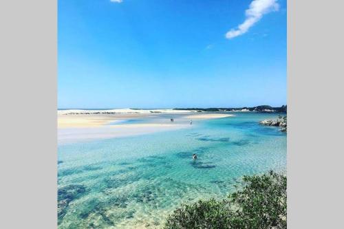 a beach in the ocean with people in the water at Emma’s Place in Sawtell