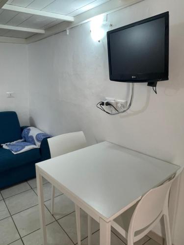 a living room with a white table and a tv on the wall at Casetta Rosy in Ostuni