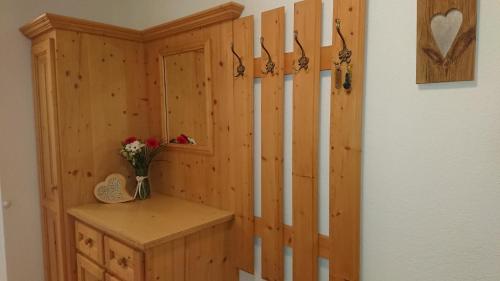 a bathroom with a wooden wall with a vase of flowers at Ledererhof in Aschau