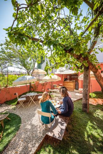 two people sitting on a bench under a tree at toctoctoc lisboa in Lisbon