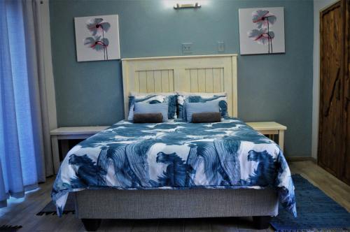 a bedroom with a bed with a blue and white comforter at Flamboyant Guesthouse in Bela-Bela