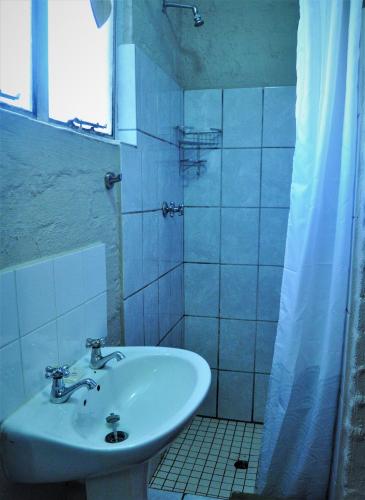 a white bathroom with a sink and a shower at Flamboyant Guesthouse in Bela-Bela