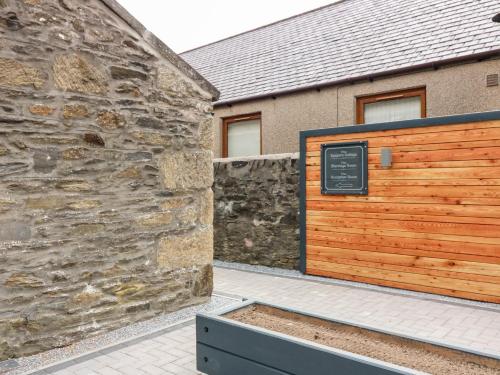 a building with a wooden gate and a stone wall at Council Chambers at The Institute Executive Apartments in Keith