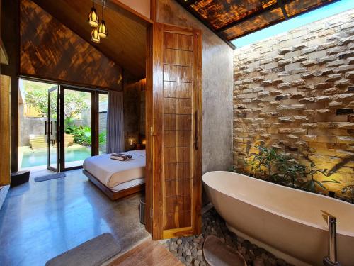 a bathroom with a bath tub and a bedroom at Batatu Villas in Kuta Lombok