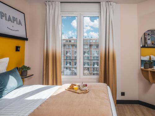 パリにあるHôtel Piapiaのベッドと大きな窓のある寝室