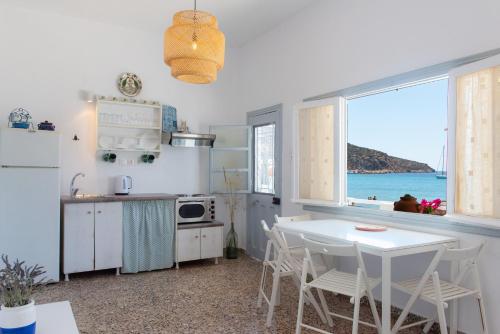 cocina blanca con mesa y vistas al océano en Grandma's sifnos house, en Platis Yialos Sifnos