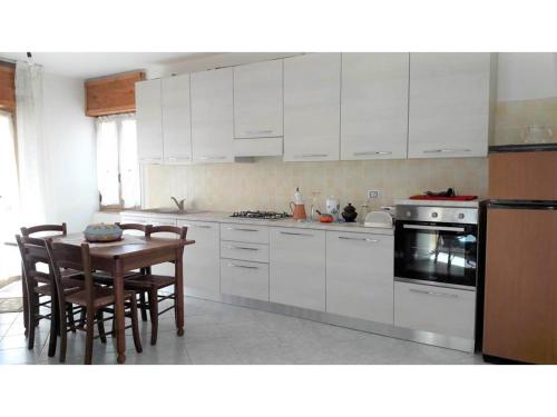 uma cozinha com armários brancos e uma mesa e cadeiras em Costa vacanze in low cost - IUN P2923 em Villaputzu