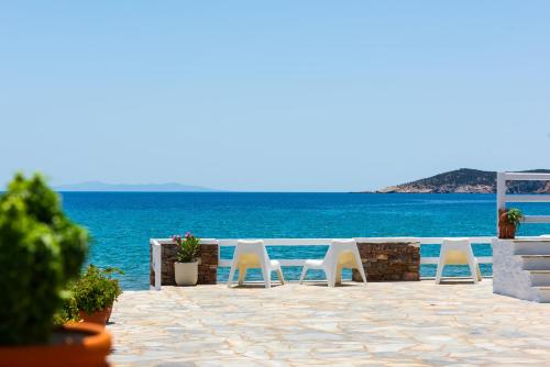 a row of white chairs on a patio overlooking the ocean at Ammos Sifnos Village in Platis Gialos
