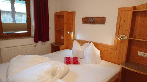 a bedroom with a bed with white sheets and a window at Ledererhof in Aschau