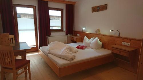 a bedroom with a bed with white sheets and pillows at Ledererhof in Aschau