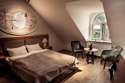 a bedroom with a bed and two chairs and a table at RATUSHA craft rooms in Kamianets-Podilskyi