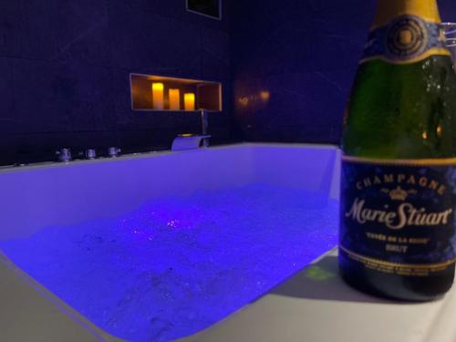 eine Flasche Wein neben einer Badewanne mit lila Flüssigkeit in der Unterkunft Lorient Love Room Le King Size in Lorient