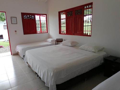 two beds in a room with two windows at Finca Hotel Santana Campestre Quindio in Quimbaya