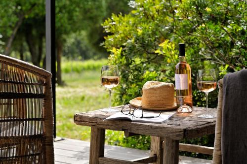 a bottle of wine and two glasses on a wooden table at Domaine de Peretti della Rocca in Figari