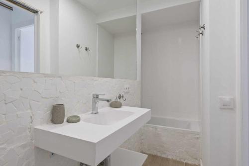 ein weißes Badezimmer mit einem Waschbecken und einem Spiegel in der Unterkunft Apartment Gaudi in Sitges