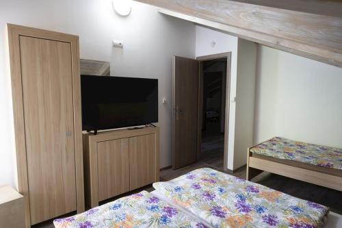 a bedroom with a flat screen tv and a bed at Chata Emily in Smižany
