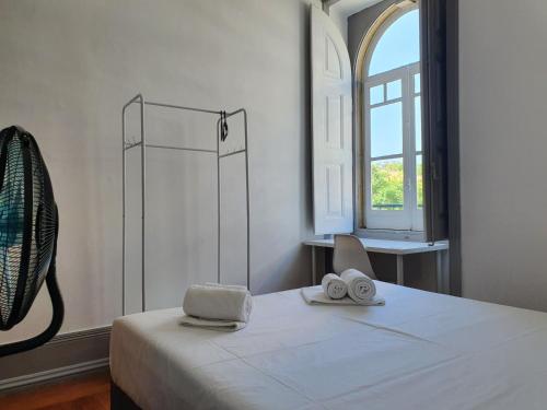 a room with a bed with two towels and a window at Baixa Terrace Hostel in Faro