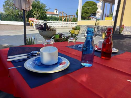une table avec un tissu de table rouge, une tasse et des bouteilles dans l'établissement B&B IRIS COTTAGE, à Campomarino