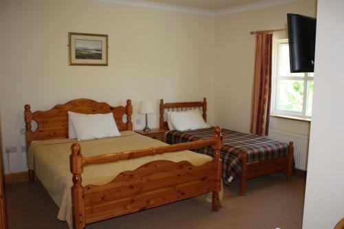 a bedroom with two beds and a flat screen tv at Dan O'Hara Farmhouse B&B in Clifden