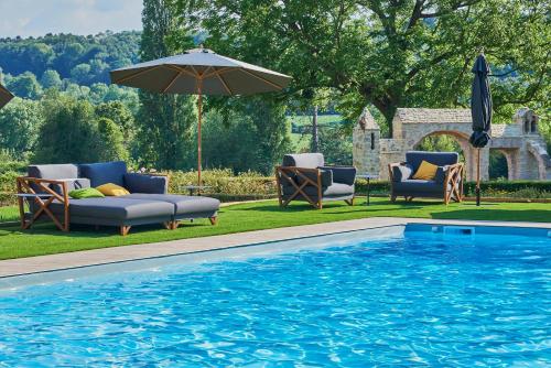 een zwembad met stoelen en een parasol naast een zwembad bij Les Jardins de Coppélia in Pennedepie