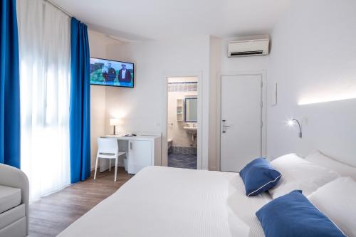 a bedroom with a white bed with blue pillows at Acqua & Sale Hotel in Cervia