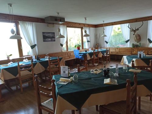 un comedor con mesas y sillas azules y ventanas en Albergo Miravalle, en Forni Avoltri