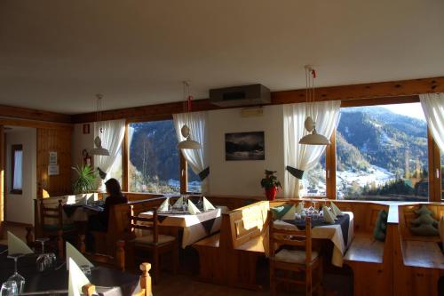 a restaurant with tables and chairs and a large window at Albergo Miravalle in Forni Avoltri