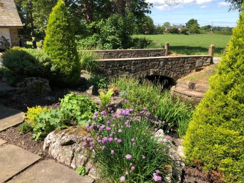 a garden with a stone bridge and flowers at Picket Post House Bed & Breakfast in Catterall